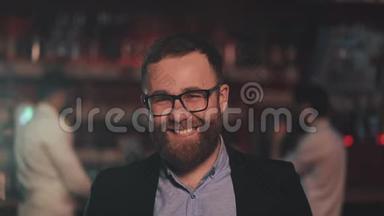 一幅微笑迷人的男人戴着眼镜在酒吧或啤酒酒吧看相机的肖像。 青年、友谊的概念